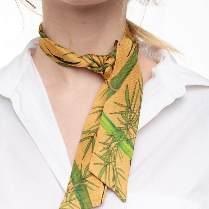 Model wearing the Bamboo silk twilly around the neck, emphasizing the natural green and beige palette. Luxury accessory for all seasons.