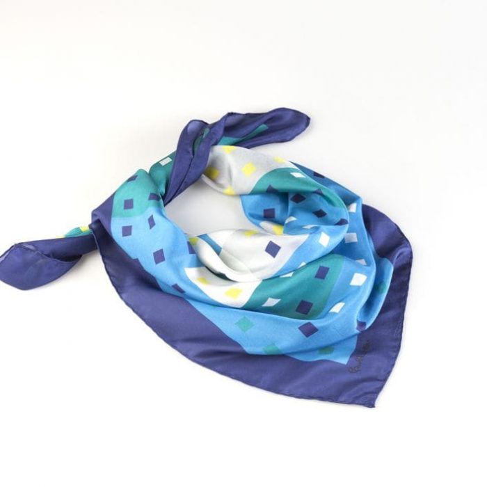 Stacked 'Patio de los Azulejos' silk square scarves, emphasizing the cooling effect of the blue frame contrasted with the inner greens and yellows.