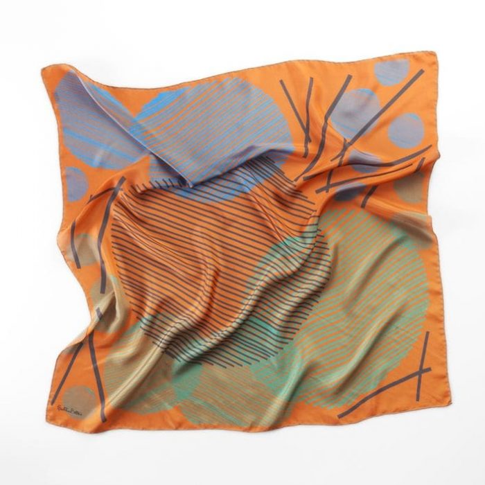 Detail of the 'Sphere in the sky' scarf, focusing on the vibrant orange texture and the dynamic diagonal lines within the geometric circles.