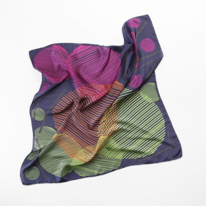 Close-up of the deep blue 'Sphere in the sky' scarf, showing the fine lines and color details representing the metal and light of the city