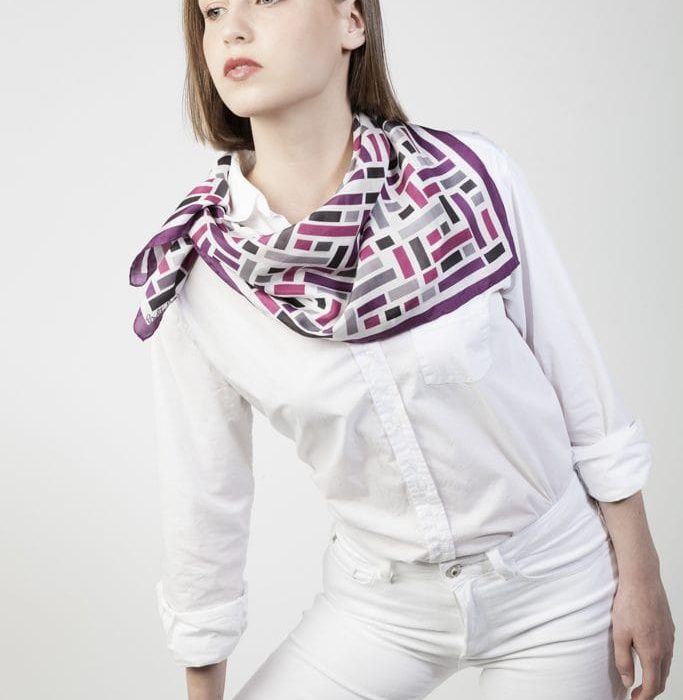 Wild West silk scarf tied as a hair accessory, adding a vibrant touch of purple and violet to the outfit. Versatile luxury accessory.