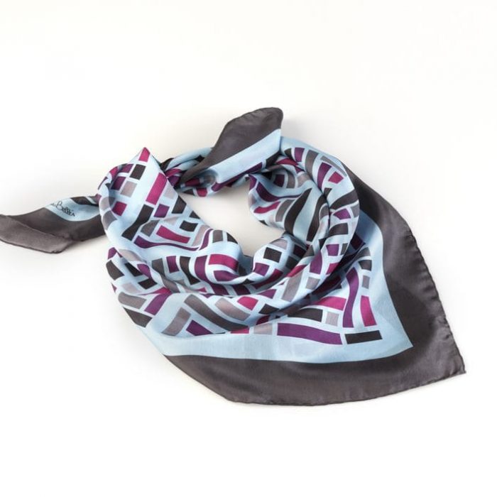 Folded Wild West silk scarf in blue, emphasizing the concept of dynamism and the shared destiny of diverse elements in the design