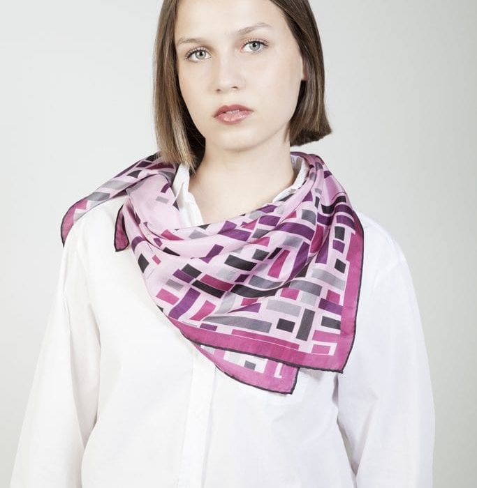 Wild West silk scarf tied as a scarf accessory, adding a vibrant touch of purple and violet to the outfit. Versatile luxury accessory.